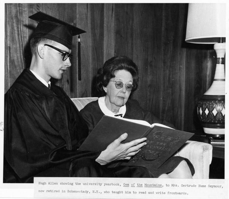 Hugh Allen showing the university yearbook 'Gem of the Mountains' to Gertrude Hume Seymour at the 1964 Commencement.