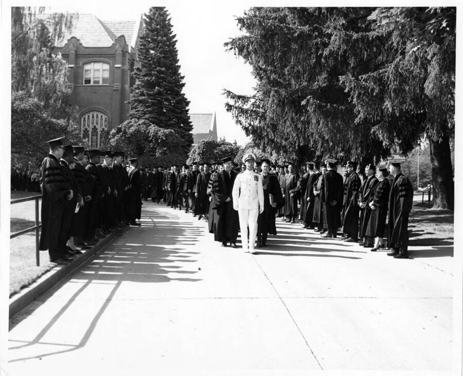 Captain Harry E. Davey leads the academic procession past the Memorial Gymnasium for the 1966 Commencement. Photographer Publications Deparment