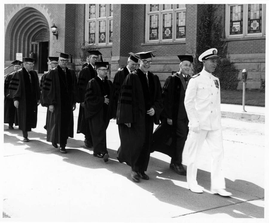Captain Harry E. Davey leads the academic procession past the Memorial Gymnasium for the 1966 Commencement. Photographer Publications Deparment