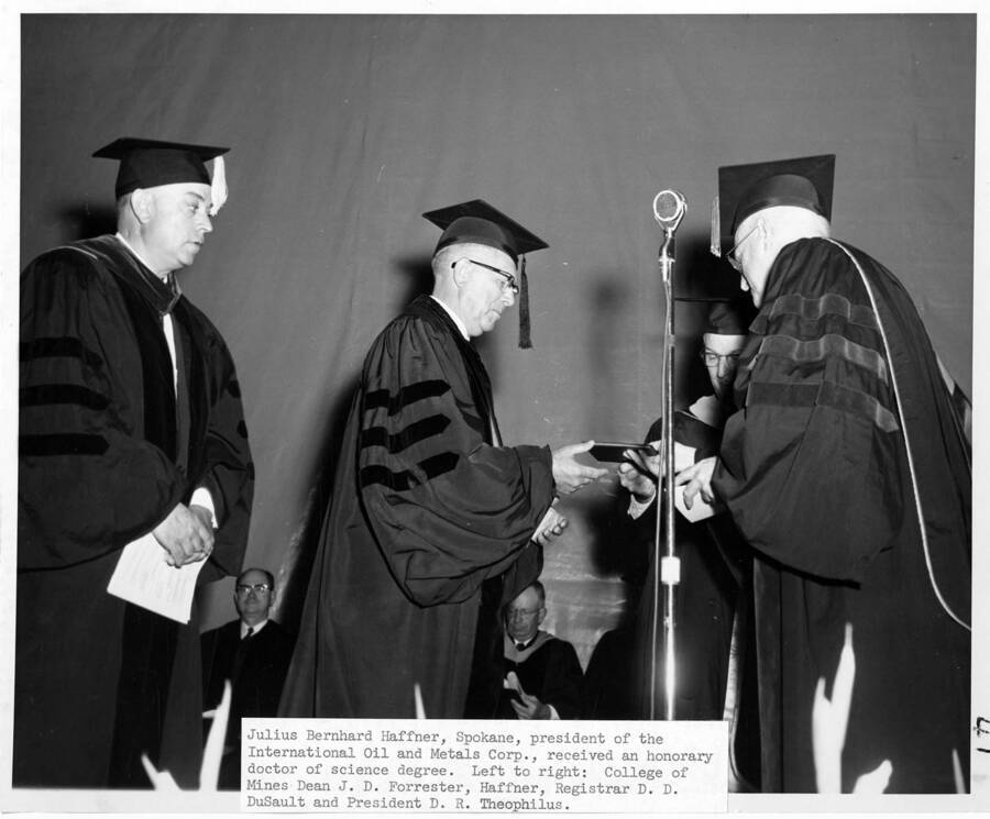 Julius Bernhard Haffner receives an honorary Doctor of Science degree during the 1956 Commencement ceremony. Also on stage are College of Mines Dean J.D. Forrester (left), Registrar Donald Dudley DuSault (behind), and University of Idaho President Donald Theophilus (right). Photographer Publications Department;