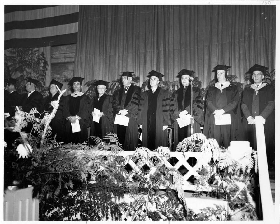 Platform group stands together in their caps and gowns during the 1953 Commencement ceremony. Photographer Publications Department