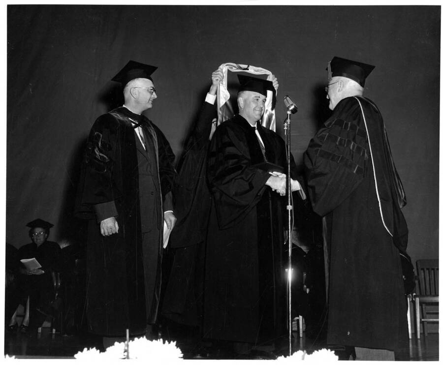 Clayton Loosli receiving an honorary Doctor of Science degree from University of Idaho President Donald Theophilus during the 1958 Commencement ceremony. Dr. Boyd A. Martin stands on the left.