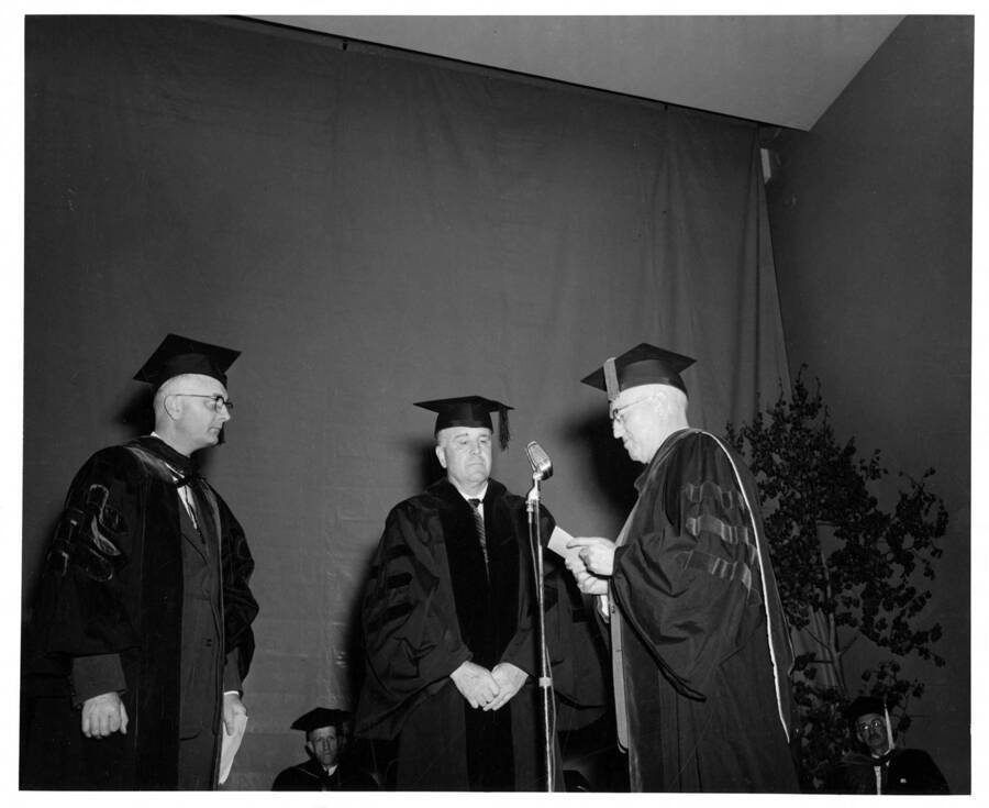 Clayton Loosli receiving an honorary Doctor of Science degree from University of Idaho President Donald Theophilus during the 1958 Commencement ceremony. Dr. Boyd A. Martin stands on the left.