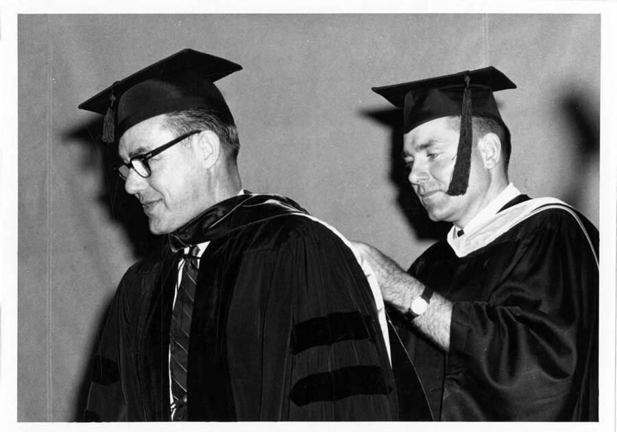 Registrar Frederick L. O'Neill adjusts the hood of Doctor of Laws degree recipient Governor Robert E. Smylie during the 1966 Commencement ceremony.