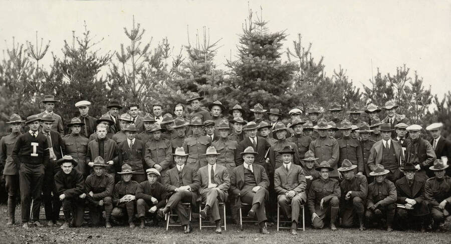 A formal group portrait of the Associated Foresters seated and standing in front of a tree nursery.