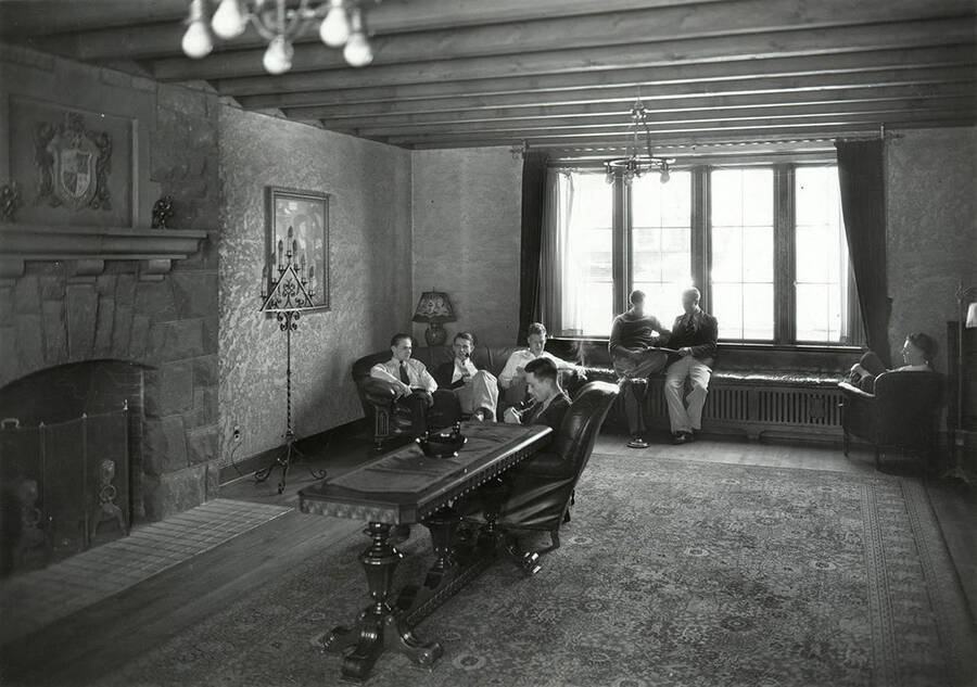 Students sitting around the living room of the Delta Chi houses, located on the southeast corner of University and Elm Streets.
