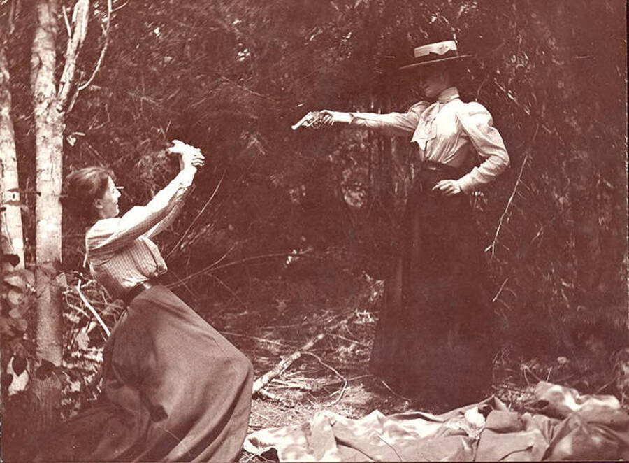 Two women stage a dramatic interpretation of a shooting.
