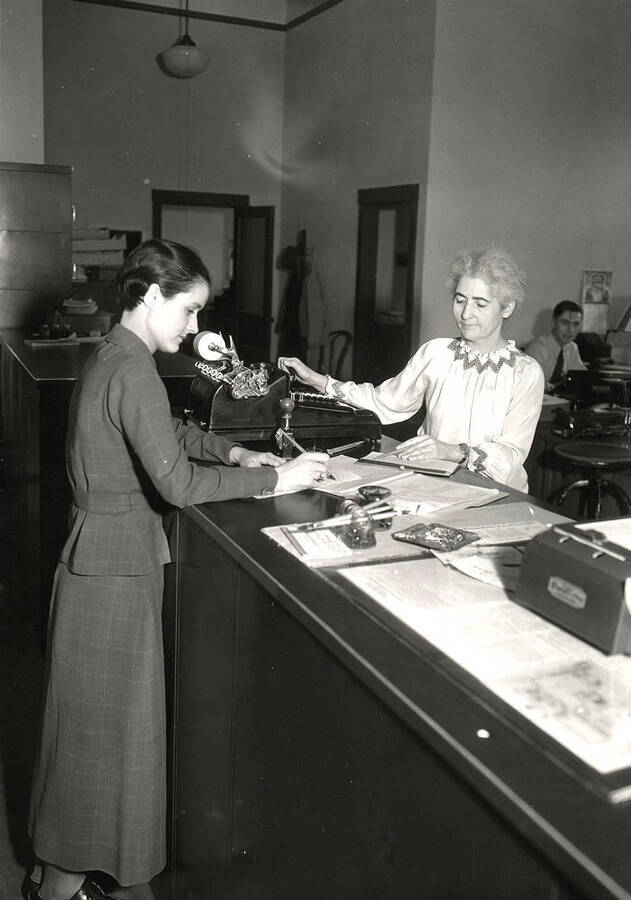 Jean Lucile Pence pays Amalie Baring, the cashier, for her registration fees. Jean Lucile Pence was the 2290th student to register for classes, representing an increase over the 1934 enrollment record.