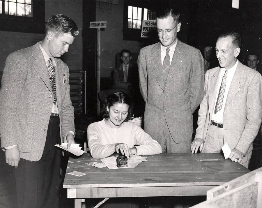 An unidentified student registers for classes while University President Jesse Buchanan looks on; D.D. DuSault, Registrar, watches from the far right.