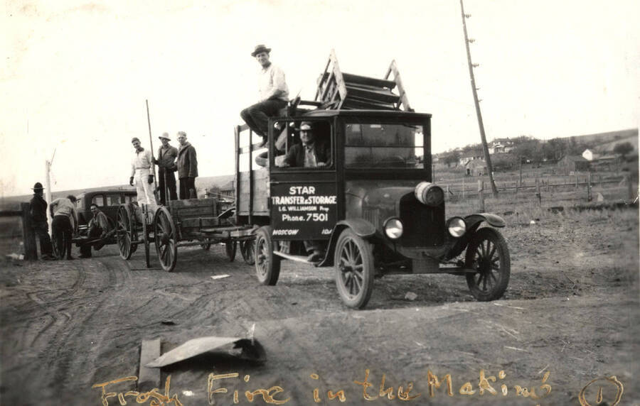 Men stand on trailers while loading supplies for theHomecoming Freshman bonfire. The caption on the photograph reads: 'Frosh Fire in the Making'.