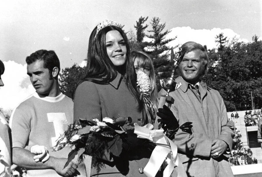 Glennis Conner, Homecoming Queen, holds a bouquet of flowers and an award.