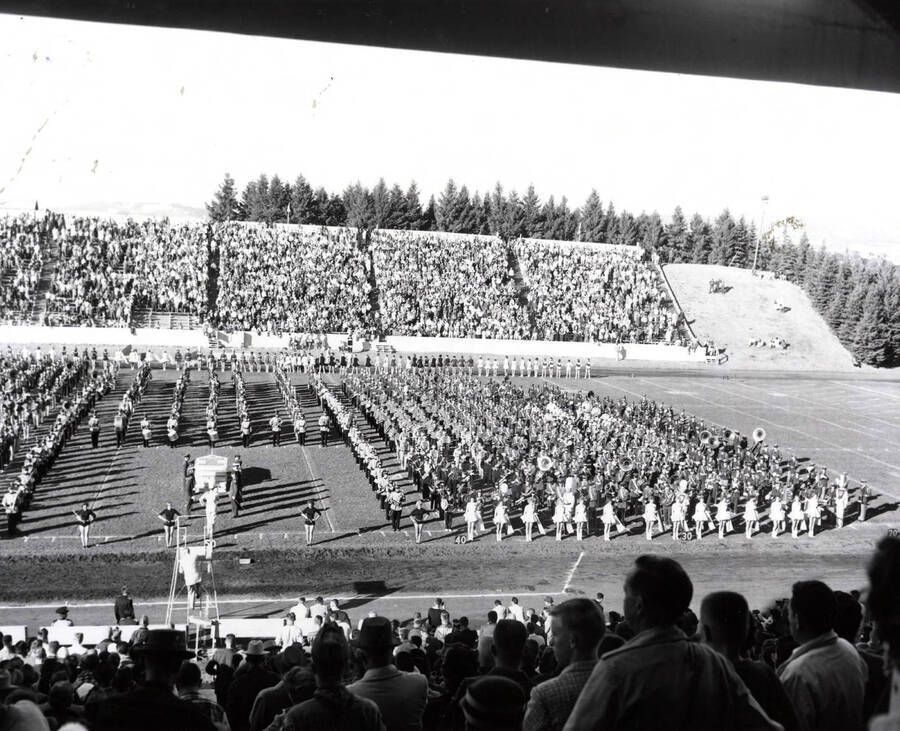 The Vandal Marching Band performs from a block formation on the field. Other regional high school bands can be seen in the formation.