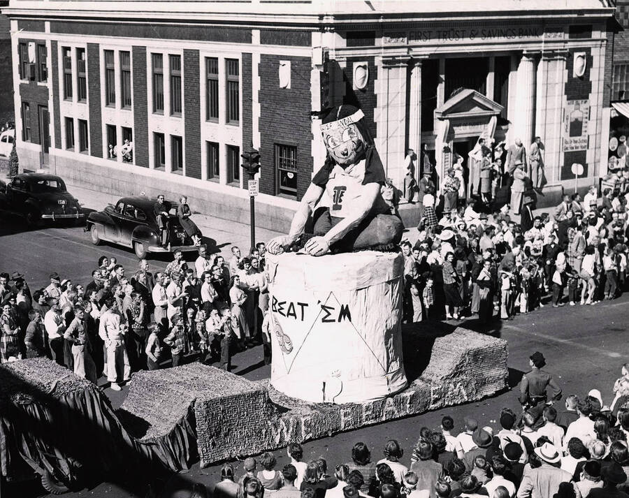 Delta Gamma winning float during the Homecoming parade, featuring a portrayal of a Native American sitting on a drum and the phrase 'We Beat Em'.