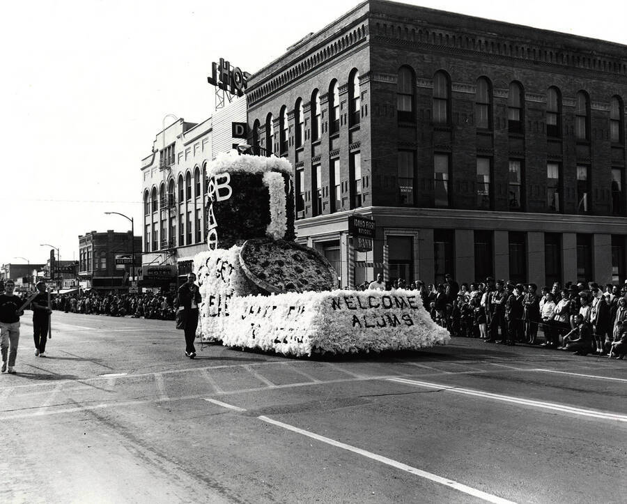 A pint of beer and a pizza sit on top of an unassociated float in the Homecoming parade. One of the captions reads: 'Welcome Alums'.