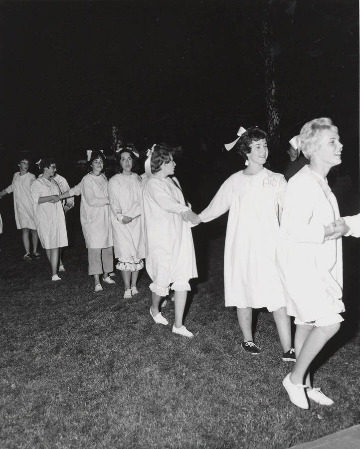 Members of Alpha Phi sorority wearing matching white gowns participate in the pajama parade the night before the Homecoming game.