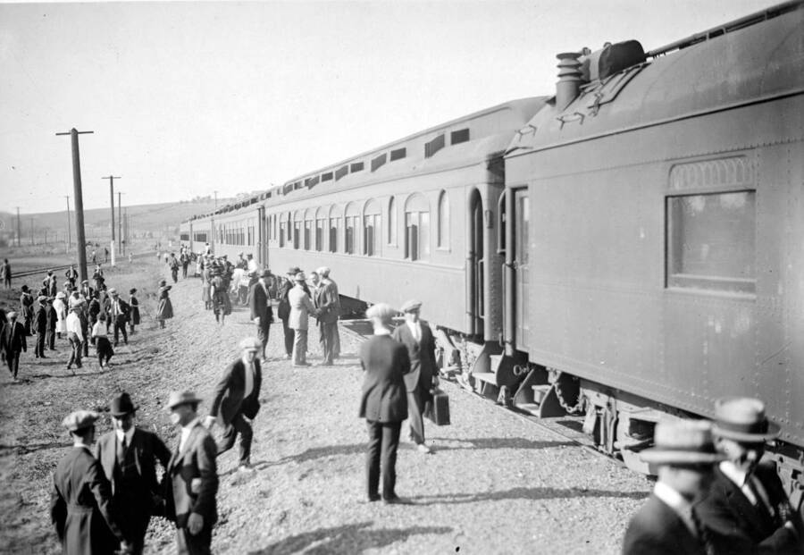 A closer photo of the Student Special train as it arrives from southern Idaho. Groups of men stand talking while others make their way toward it.