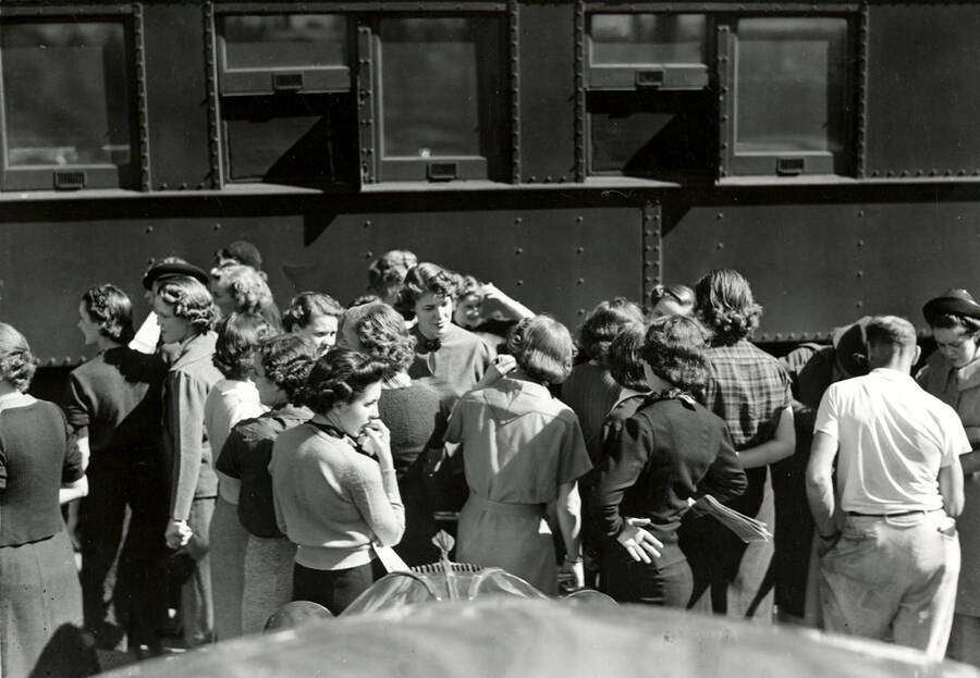 A group of people stand waiting outside of the Student Special train.