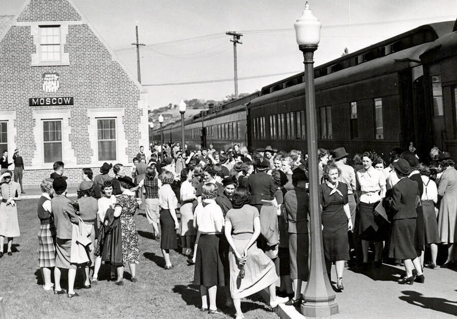 Groups of people stand waiting outside the Moscow Union Pacific Railroad Depot.
