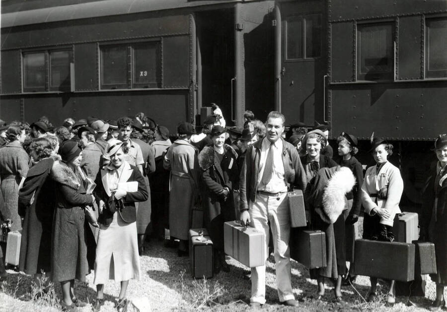 A conglomerate of people stand outside the Student Special train and stop to have their photograph taken.