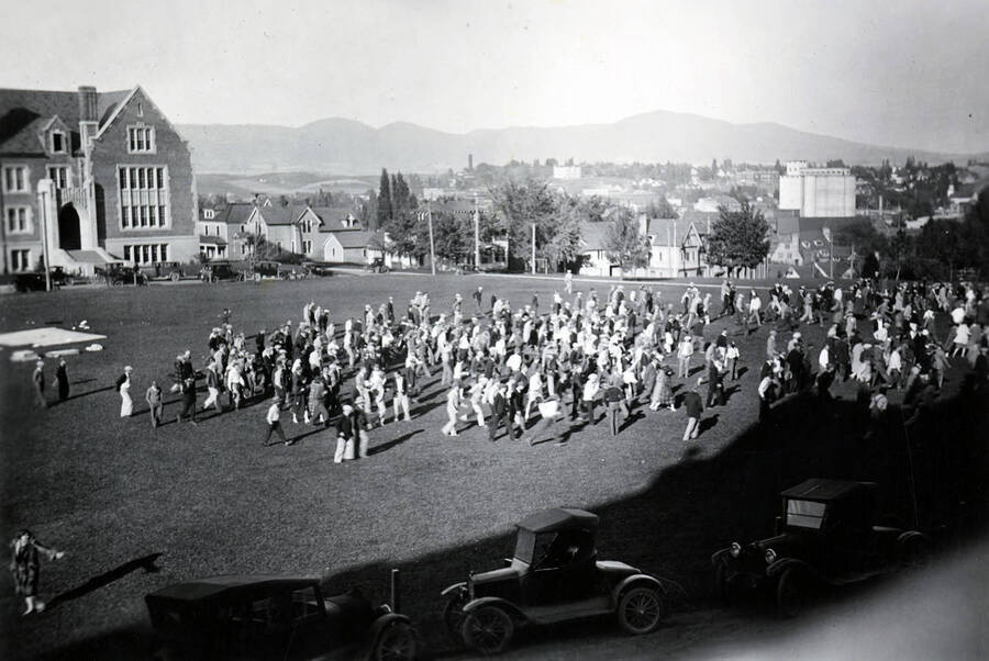 A crowd of people marches from the Administration lawn toward Greek Row following the annual freshman-sophomore Hulme fights.