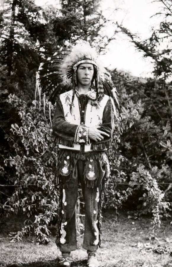 A man poses with crossed arms, sporting the wear of a Native American chief for the Light on the Mountains pageant.