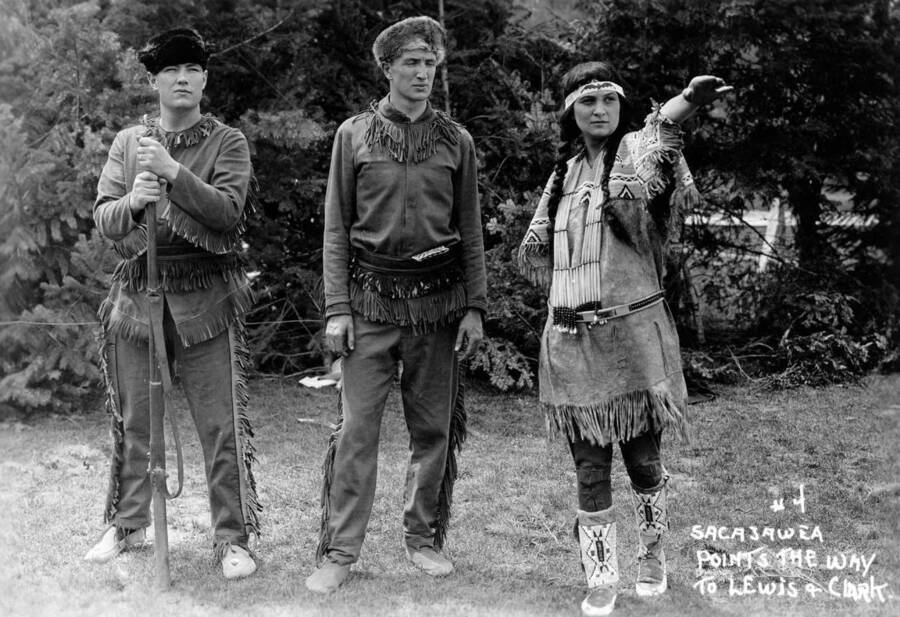 Jeannette Greve poses as Sacajawea and points into the distance while William G. Guernsay and Wilbur C. Disney pose as Meriwether Lewis and William Clark for the Light on the Mountains pageant. Caption reads: "#4 Sacajawea Points the Way to Lewis &amp; Clark."