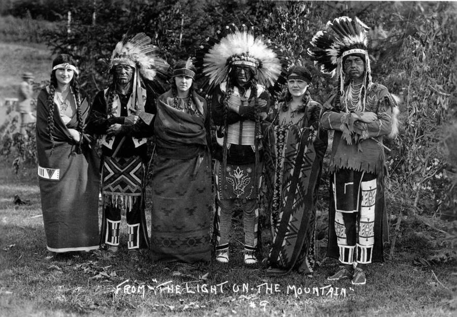 Five people pose as Native Americans, Vivian Kimbrough poses as Speaking Eagle and Pauline Pence poses as Nez Perce Jane for the Light on the Mountains pageant. Caption reads "From 'The Light On The Mountain', #9."
