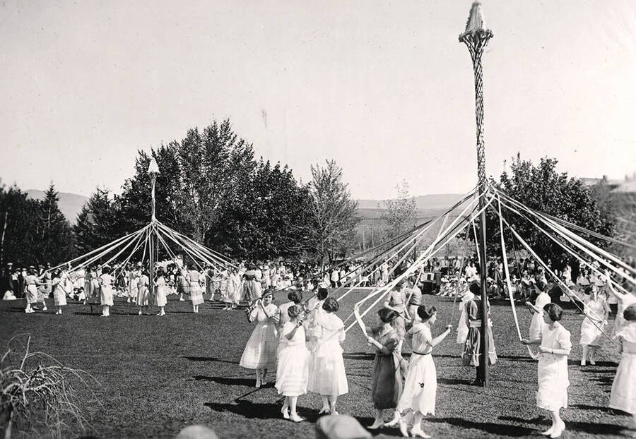 Students participate in the Maypole dance, spinning ribbons around light-posts for the Campus Day tradition.