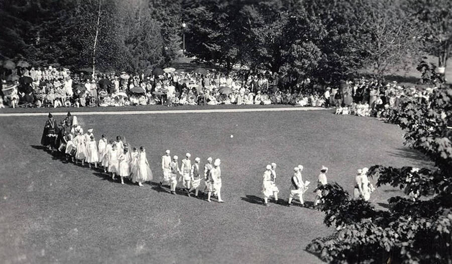 Students walk in a line, participating in the procession of the May Queen during Campus Day.
