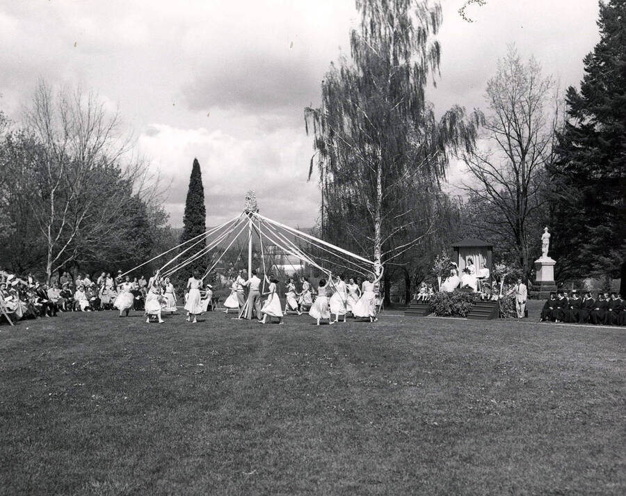 A far-shot of students winding the maypole during Idaho's Mother's Day celebrations, the Spanish-American War memorial is seen in the background.