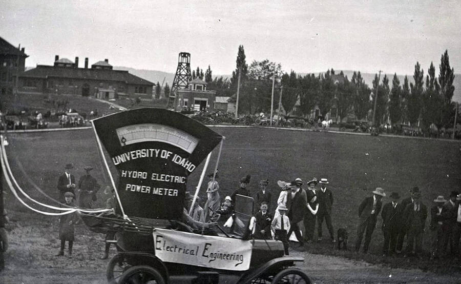 The electrical engineering float passes in front of the Administration Building during Idaho's Campus Day parade. Caption on float reads: "University of Idaho Hydro Electric Power Meter."