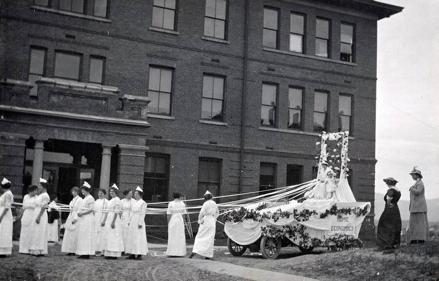 Miss Hoover stands in front of Morrill Hall, looking at the home economics float constructed for Idaho's Campus Day parade.