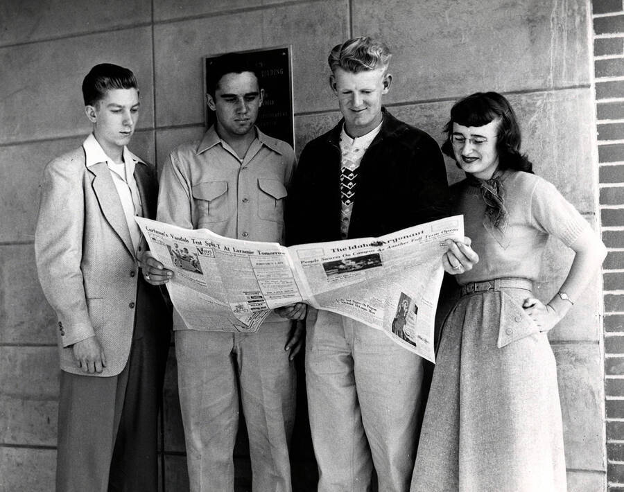 Staff members read an issue of Idaho's student newspaper, the Argonaut outside of the Student Union Building. Pictured: Lois Bush (right) and Rex Eikem (second right)