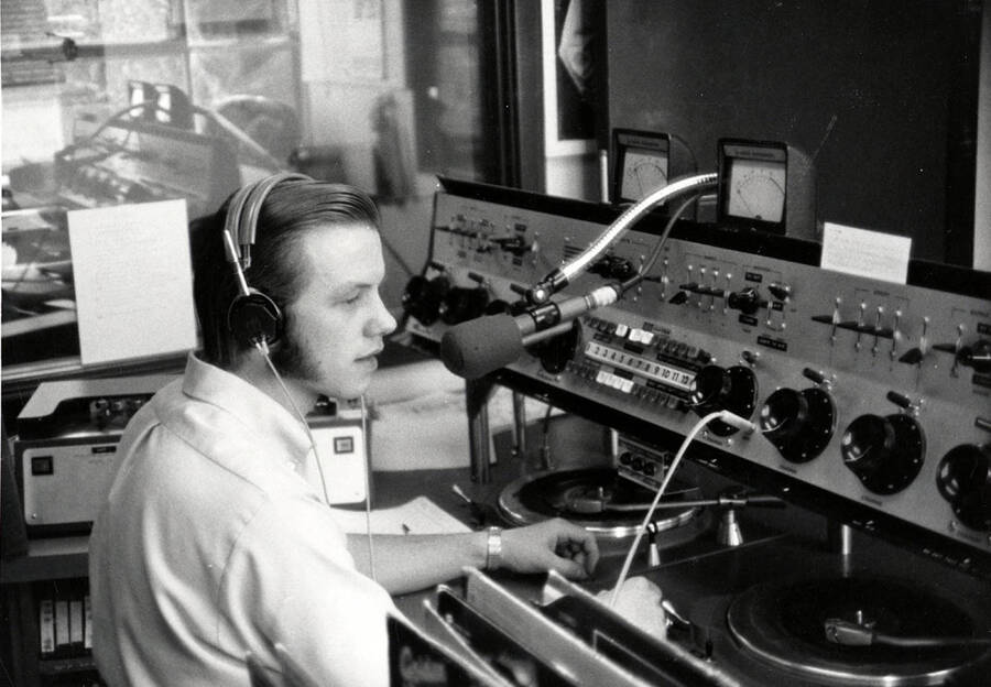 Idaho's KUOI radio manager Gerald Thaxton sits in front of a microphone, wearing headphones.