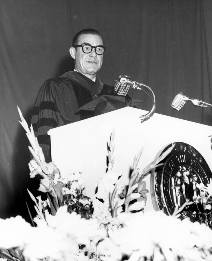 Governor Robert E. Smylie, sporting black-rimmed glasses, gives a speech at Idaho's commencement.