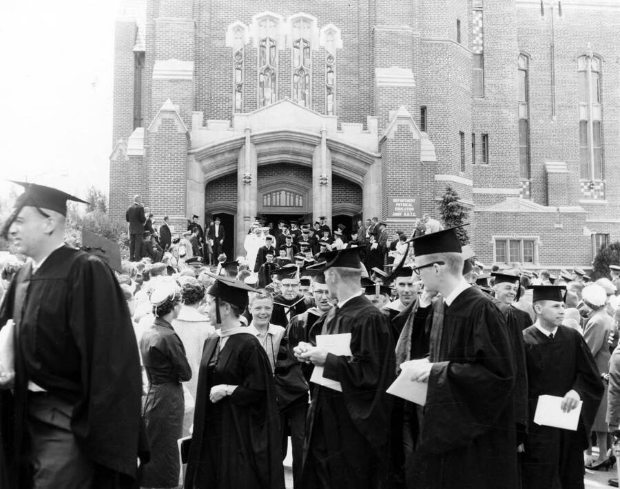 Students laugh and smile outside the Memorial Gym as they are greeted and congratulated by friends and family post-commencement.