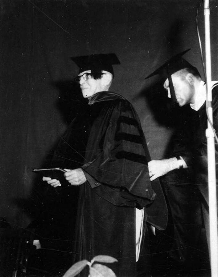 Benjamin W. Oppenheim stands on stage and receives a hood and an honorary degree.
