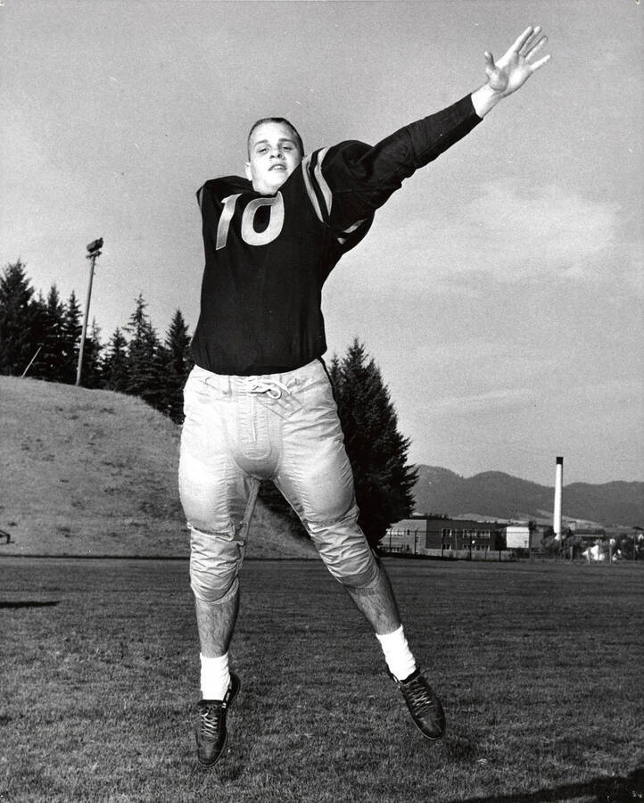 Football player Rick Dobbins (quarterback) jumping in his University of Idaho football uniform.