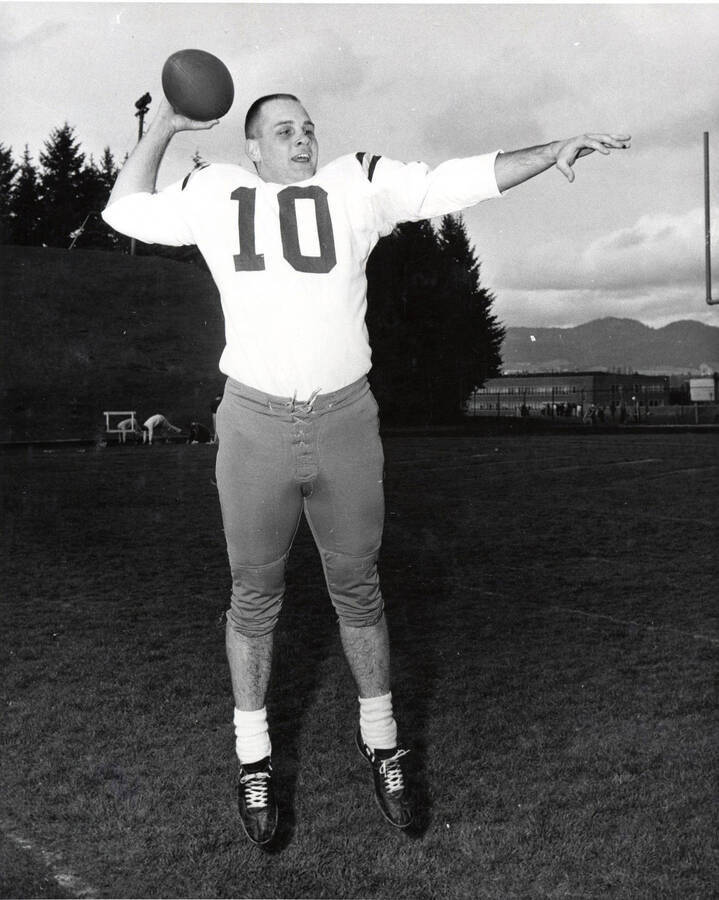 Football player Rick Dobbins (quarterback) jumping in preparation to throw the football on the field at the University of Idaho.