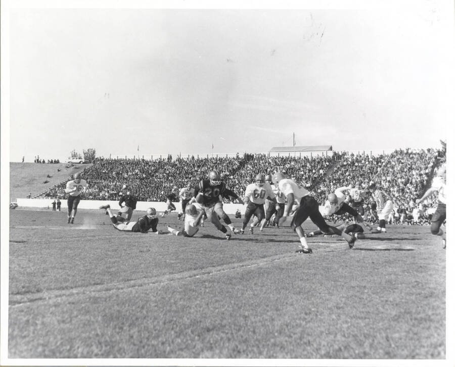A Vandal running back holds on to the ball and a defender while trudging his way forward.