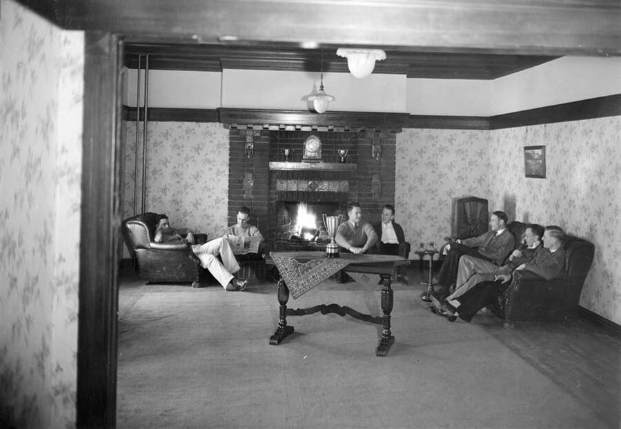Students sitting around the living room in the Kappa Sigma house, which is on the northeast corner of Blake and Sweet Avenues.
