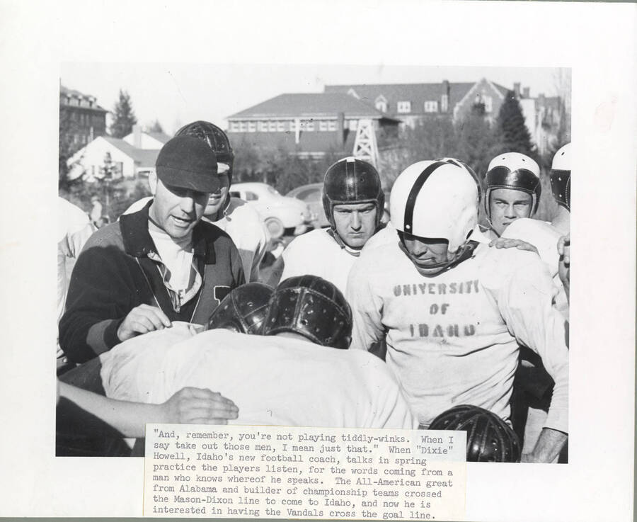 Picture shows Coach Howell giving Idaho players a speech during  practice. Caption reads: 'And, remember, you're not playing tiddly-winks. When I say take out those men, I mean just that.' When 'Dixie' Howell, Idaho's new football coach, talks in spring practice the players listen, for the words coming from a man who knows whereof he speaks. The All-American great from Alabama and builder of championship teams crossed the Mason-Dixon line to come to Idaho, and how he is interested in having the Vandals cross the goal line.'
