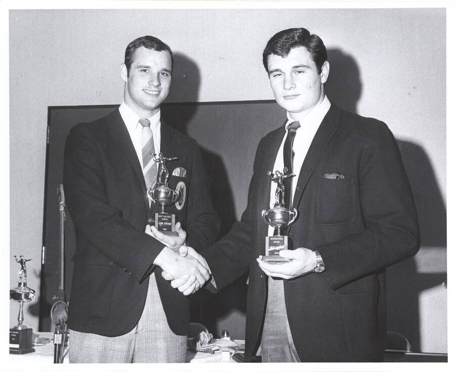 Jerry Hendren and Rob Young respectively hold their 'Most Valuable Vandal' and 'Inspirational Award' trophies while shaking hands.