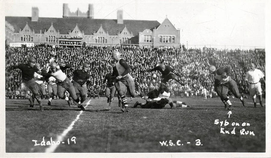 An Idaho running back takes a handoff left, pursued by a hurdling Cougar. Caption reads 'Idaho-19, Syb on an end run,  W.S.C.-3.'