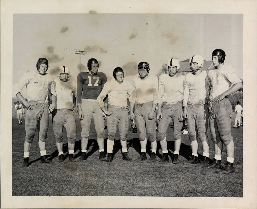 Eight Vandal football freshman pose for a picture, almost all wearing different helmets. From left to right: Jack Pring, Bill Oliver, George McCartey, Richard Peters, Bob Stephens, Loren Tedrow, Wayne Anderson and Jerry Ogle.