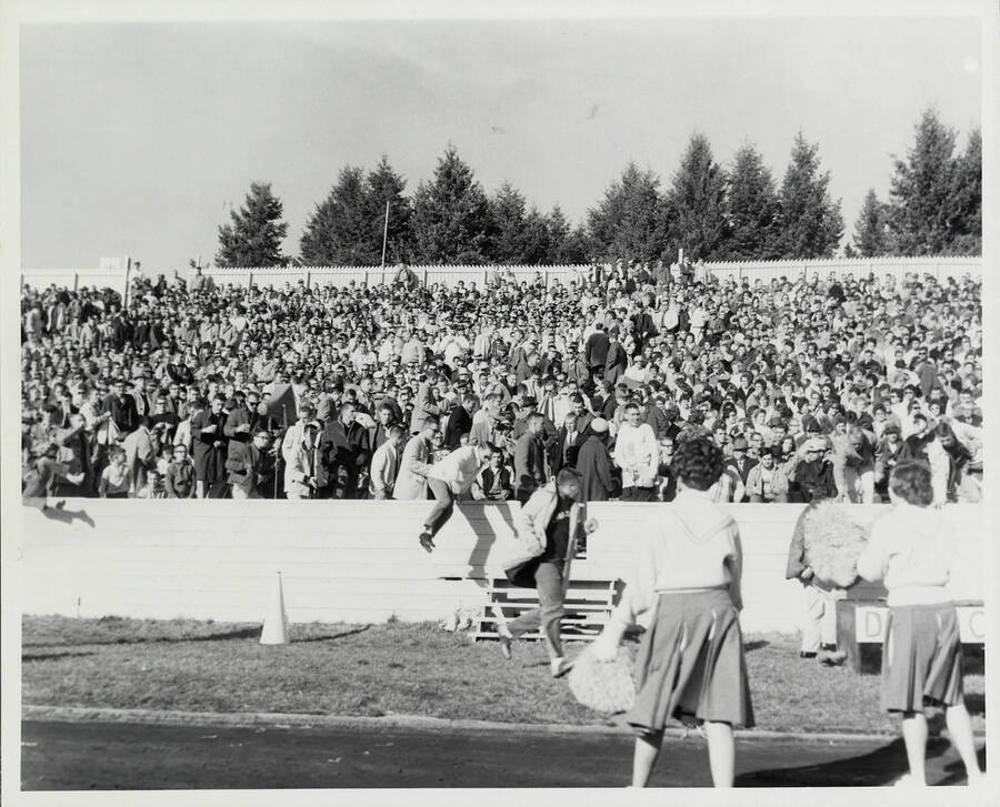 Fans stand in the bleachers in front of Idaho's cheer team. Several spectators can be seen hopping the barracade and running toward the field.