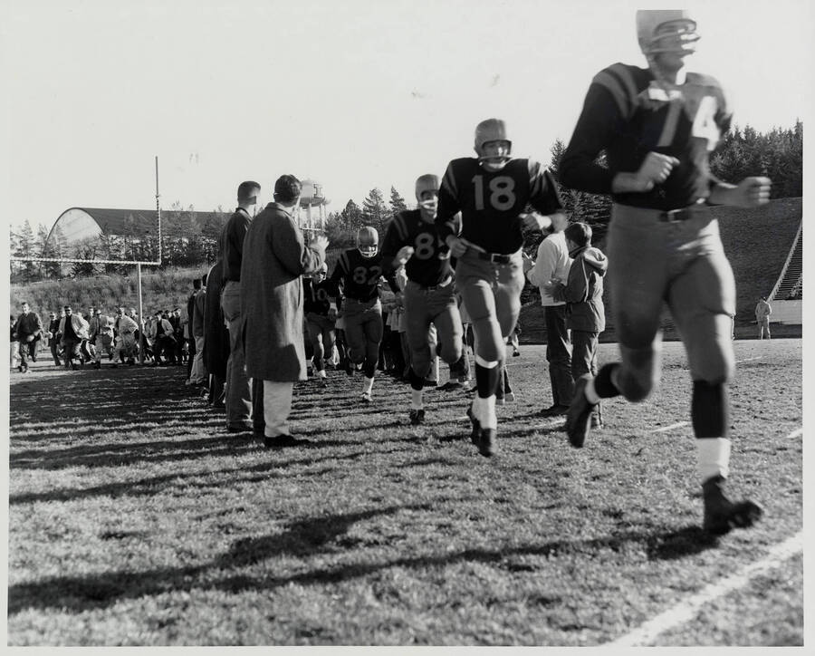 A line of Vandals storms the field between two columns of spectators. The 'I' water tower can be seen clearly in the background.