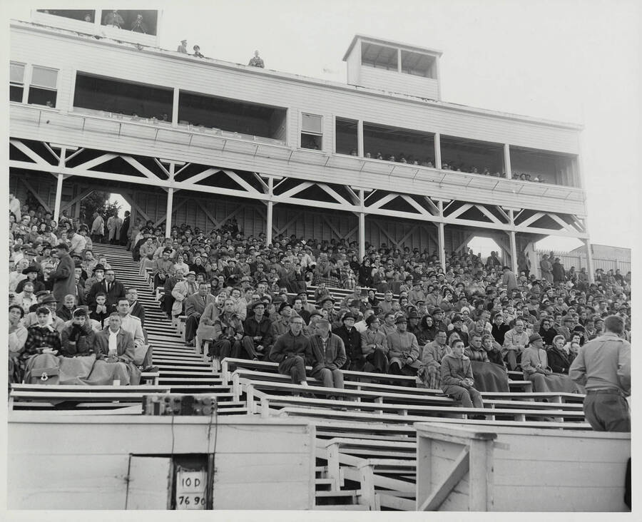 Spectators sit under the old, wooden press boxes. Most fans are wrapped in blankets or heavy coats.