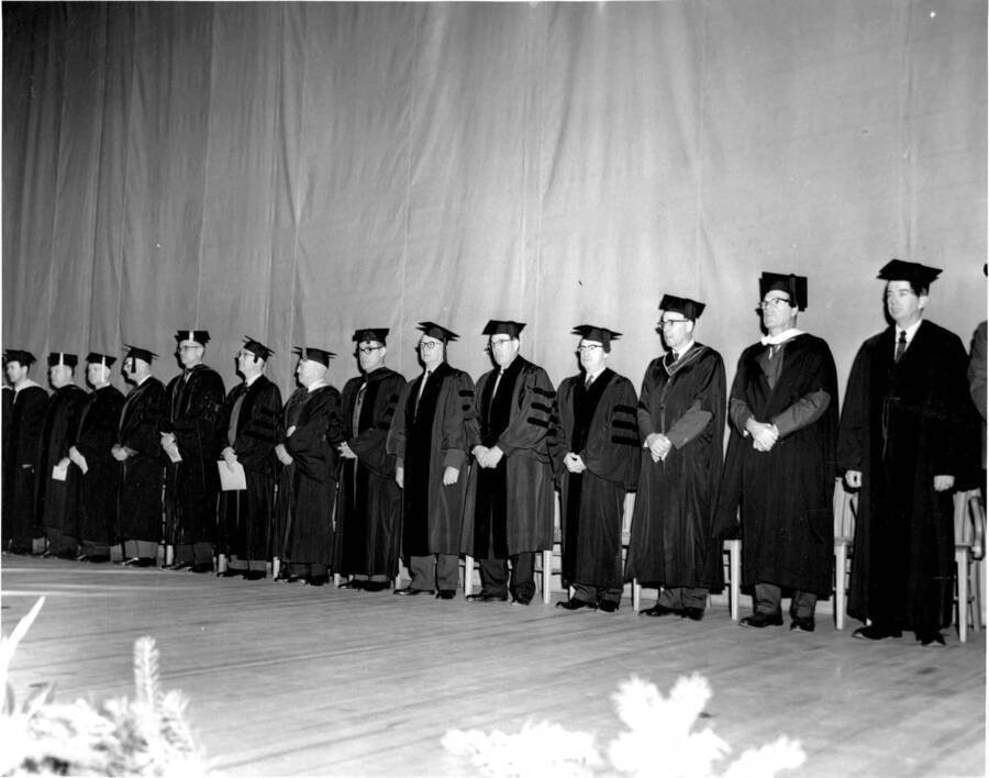 College Deans and Faculty stand for a photograph on the stage before Commencement.