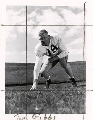 University of Idaho football player, Tom Gibbs(#19), crouching with a hand on the football field.